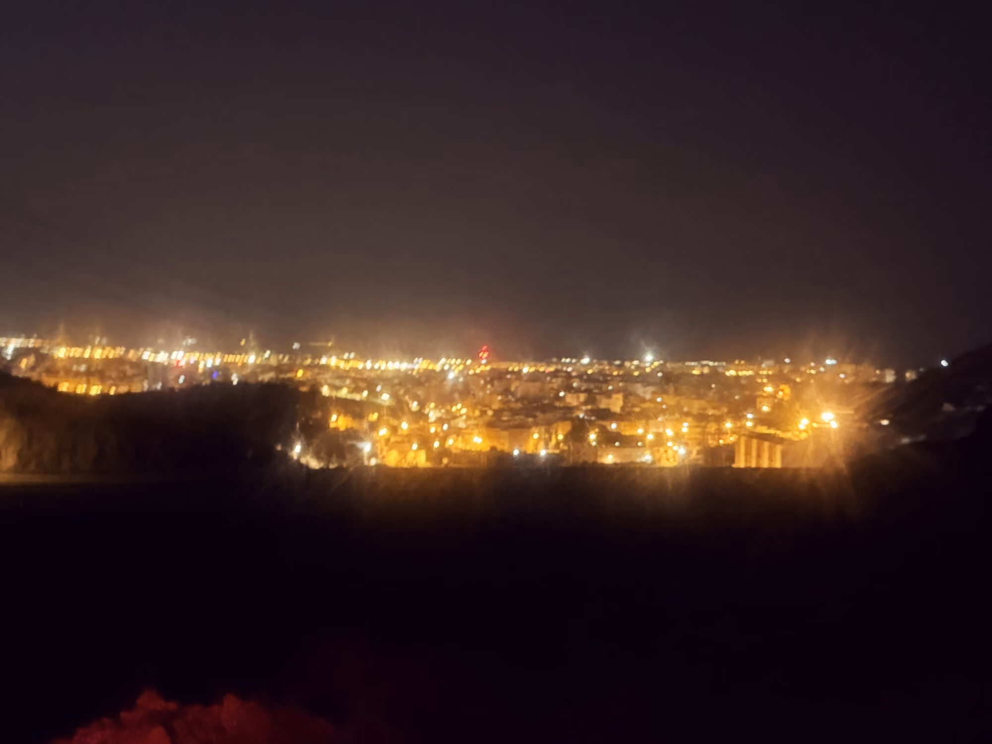 City lights of Almería at night seen from the dark hillside above.