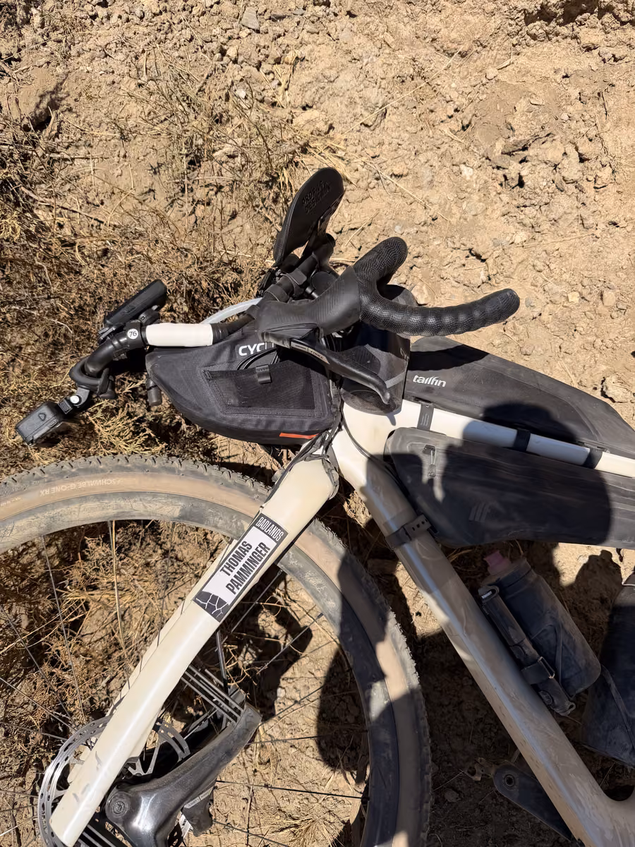 The bike lies on dry ground with its handlebar rotated down.