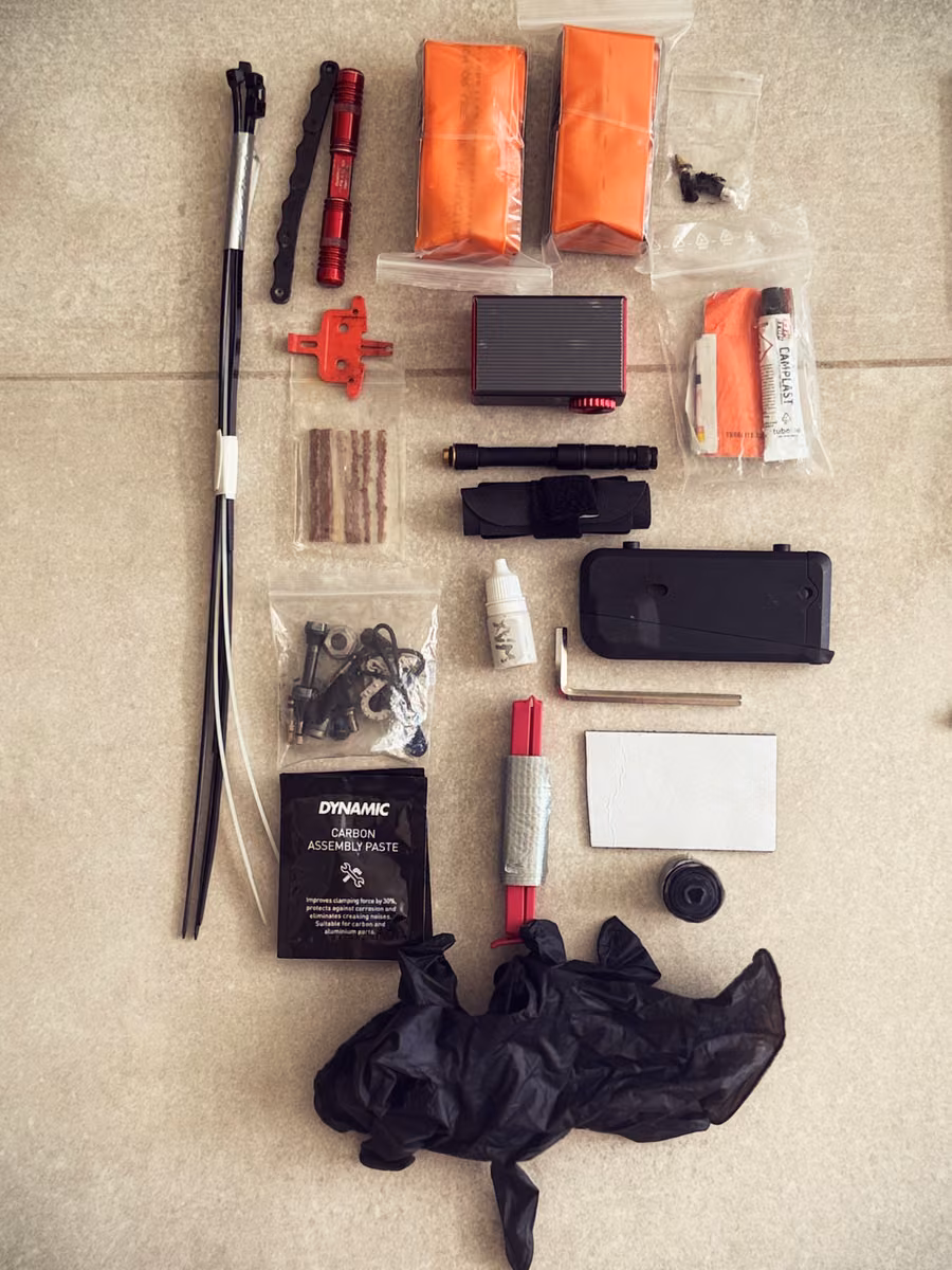 A pump, spare tubes, tire repair supplies and tools laid out on tiles.