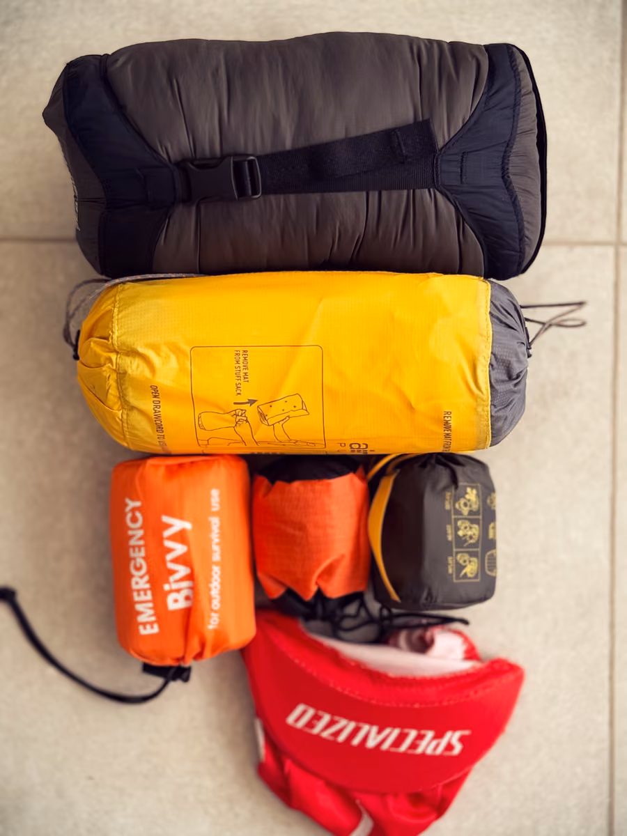 Rolled gear and gray, yellow, orange and red stuff sacks arranged on tiles.