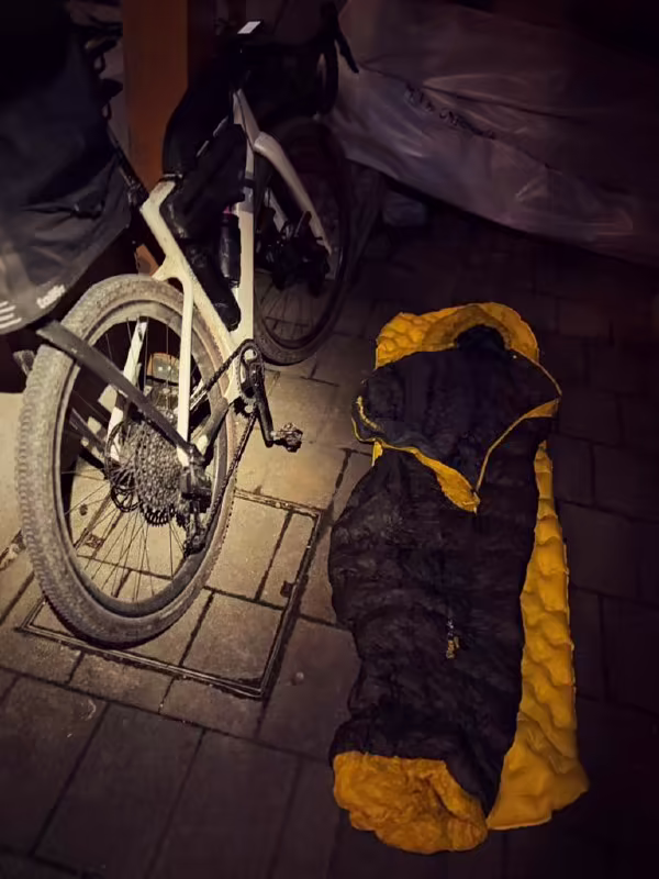 Sleeping bag rolled out next to a loaded bikepacking bike at night
